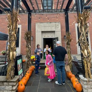 Children, accompanied by adults, walk up a pumkin-lined walk to trick-or-treat at a local business